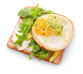 Tasty toast with avocado, fried egg and arugula on white background