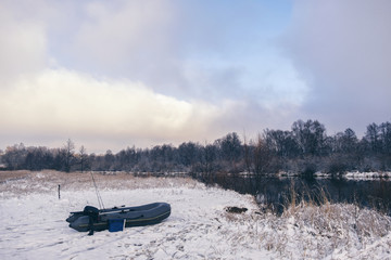 Inflatable fishing boat on the bank of a winter river.