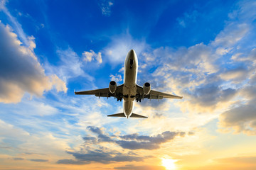 Airplane flying above dramatic clouds during sunset