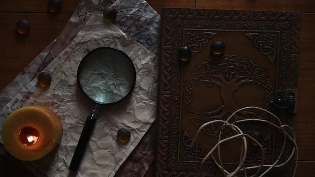 beautiful vintage background with ancient maps, a book, a candle some stones and a magnifying glass