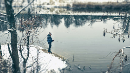 Lone fisherman on the bank of winter river.