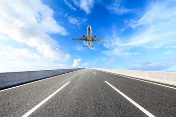 Empty asphalt road and sky flying airplane