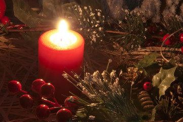 Candella natalizia. Luce soffusa della candela natalizia con decorazioni ed ornamenti sullo sfondo. Atmosfera di Natale.