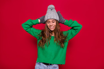 Naklejka premium Incredible girl wearing green pullover nad grey winter cap having fun with over red background with confetti. New year presents, celebrating birthday, expressing positive emotions