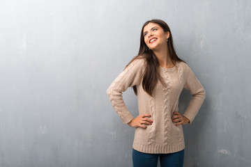 Fototapeta premium Teenager girl with sweater on a vintage wall posing with arms at hip and laughing