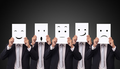five businessman holding a card with drawing facial expressions different emotion feelings face on...