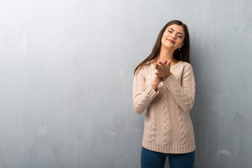 Teenager girl with sweater on a vintage wall applauding after presentation in a conference
