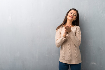 Fototapeta premium Teenager girl with sweater on a vintage wall applauding after presentation in a conference