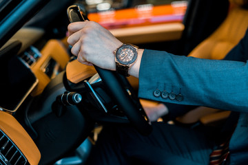 cropped image of businessman with luxury watch sitting in automobile
