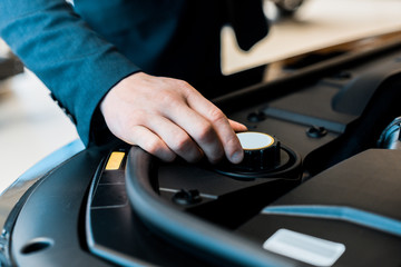 partial view of businessman checking car hood of automobile