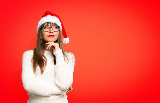 Girl with celebrating the christmas holidays thinking an idea on red background
