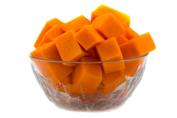 Pieces of raw pumpkin in a glass bowl. Vegetarian food. Raw vegetables. Isolated on white background. Orange flesh of ripe fruit.