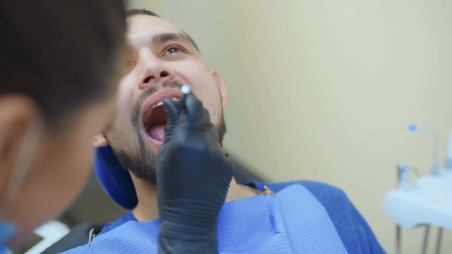 image of dentist using angled mirror while examining patient's teeth