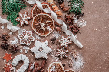 Frame with fir branches, Gingerbread cookies and Christmas decorations on dark brown paper background. Top view.