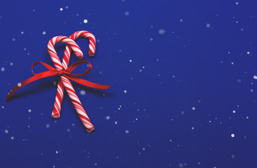Festive Christmas background with two candy canes and ribbon on blue background. Place for text.