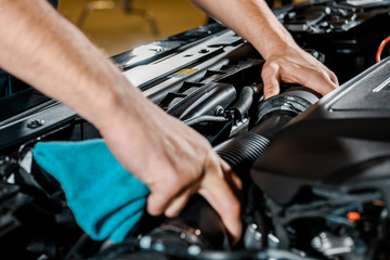 cropped shot of auto mechanic with rag checking automobile