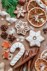 Frame with fir branches, Gingerbread cookies and Christmas decorations on dark brown paper background. Top view.