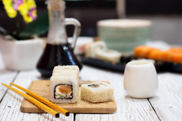 Sushi in sesame on a bamboo board. Near yellow chopsticks.
