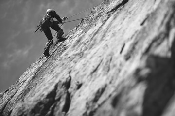 Climber climbs on the rock wall. Climbing gear. Climbing equipment. Black and white.