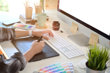 Creative designer using digital drawing tablet in studio workplace