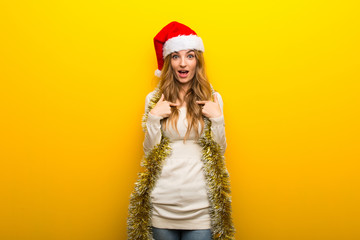 Girl celebrating the christmas holidays on yellow background with surprise facial expression