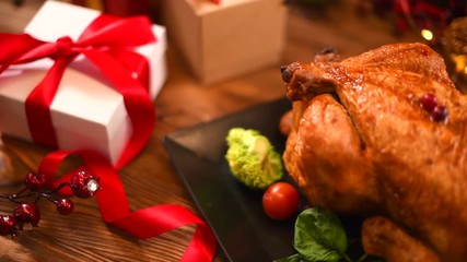 Christmas dinner. Roasted chicken on holiday table, decorated with candles and gifts. Delicious steamed roast turkey over wooden background. 4K UHD video footage 3840X2160 - Powered by Adobe