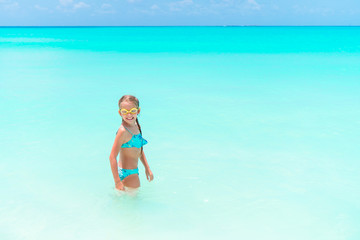 Little happy girl splashing and having fun in the shallow water. Kid in swimsuit playing with sand