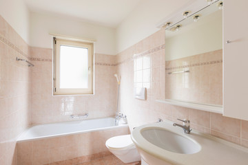 Bathroom with bathtub with clear tiles and bright window