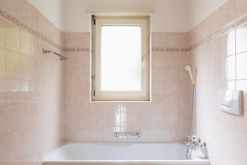 Bathroom with bathtub with clear tiles and bright window
