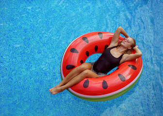 sexy girl in black bikini swimming on inflatable watermelon matt