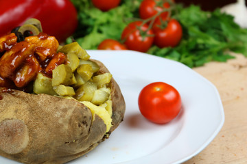 Kumpir - Traditional Turkish meal with baked potato, butter, cheese, cucumber, chicken with barbecue sauce, and hot spices
