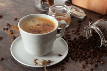 a cup of black coffee, cinnamon and coffee beans.