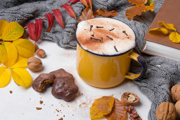A mug of hot coffee surrounded by autumn leaves.