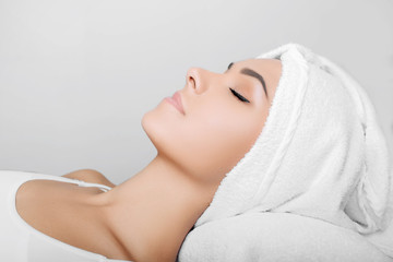 Fototapeta na wymiar woman with clean fresh face, with towel on head, relaxing after spa receiving treatment. Women with perfect skin enjoying a skin care treatment