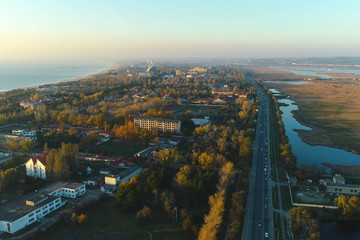 Fototapeta premium Beautiful evening view of coastal city with roadway and wet meadows. Aerial photo.