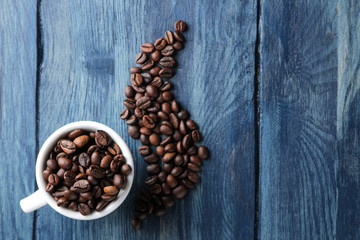 coffee cup for espresso and coffee beans in the form of smoke on a blue wooden table with space for an inscription