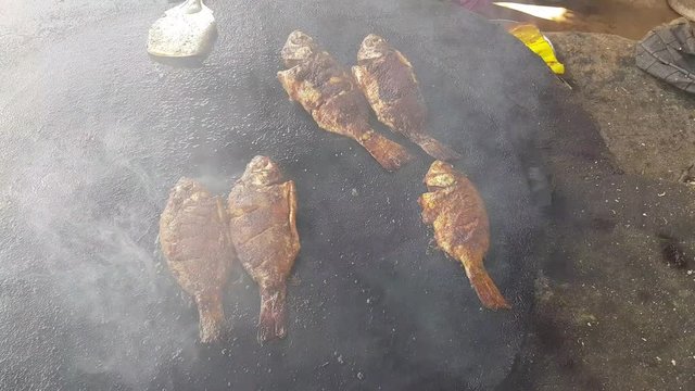 Spicy fish being fried in a big cast iron pan