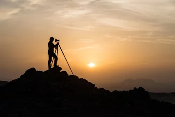 Fototapeten Silhouette eines männlichen Landschaftsfotografen, der mit einem Stativ fotografiert © Sebastian
