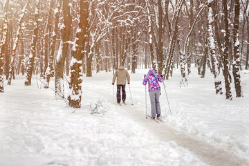 Fototapeta na wymiar Couple of people enjoying cross-country skiing in city park or forest in winter. Family Sport outdoor activities in winter season concept. Healthy lifestyle