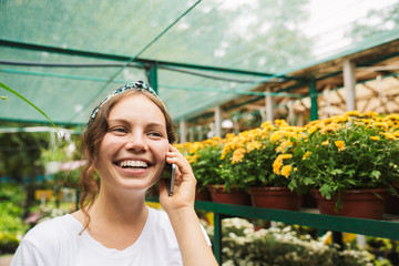 Fototapeta premium Cheerful young woman gardener talking on mobile phone