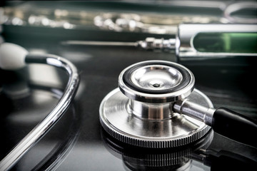 Stethoscope next to syringe of metal in a laboratory, conceptual image