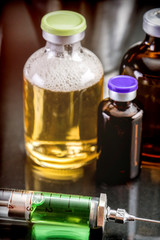 Vials of different size next to syringe of metal in a laboratory, conceptual image