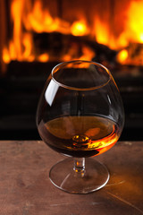 glass of cognac in front of fireplace