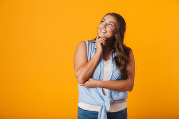 Happy young woman standing isolated over yellow