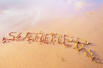 Summer letters handwritten in sand on beach