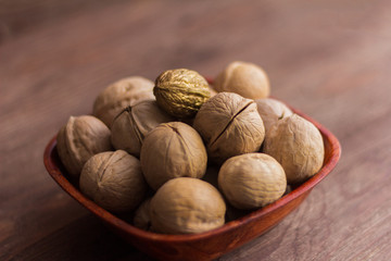full bowl of walnuts on wooden background