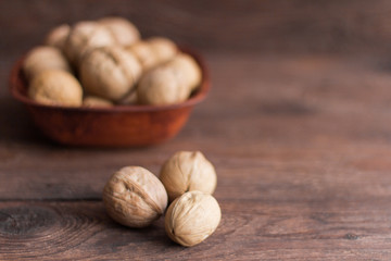 full bowl of walnuts on wooden background