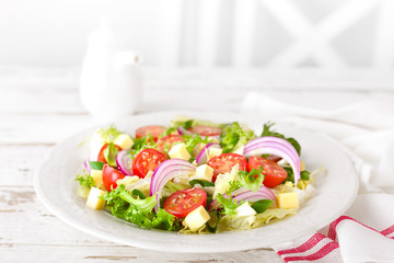 Fresh vegetable salad with tomatoes, lettuce, onion and cheese on white wooden background. Healthy vegetarian food