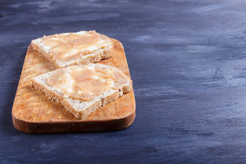 sandwiches with pollock roe on a wooden kitchen board against black background
