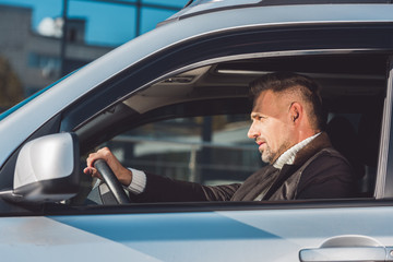 Handsome driver sitting in car and holding steer